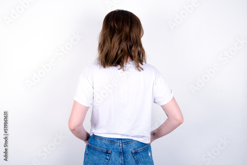 The back view of young caucasian woman wearing white T-shirt over white background Studio Shoot.