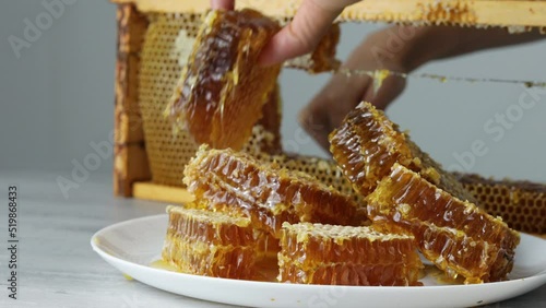 Cutting of piece of honey from open honeycomb in wooden frame on the table photo