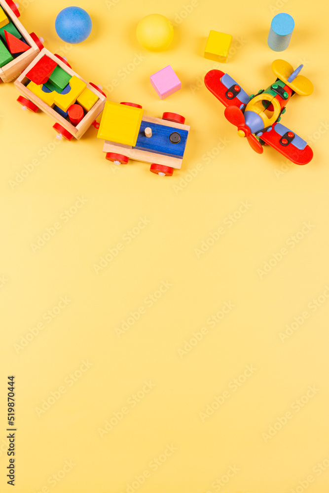 Obraz premium Baby kids toys. Wooden train, airplane, colorful blocks and balls on yellow background. Top view, flat lay