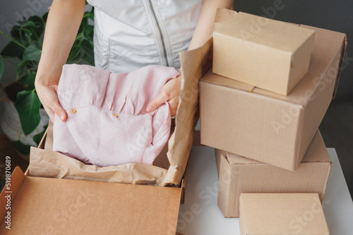female entrepreneur sells children's clothes online and packs them in boxes to be sent to a delivery service. small business selling goods on the Internet on the marketplace. handmade or factory-made