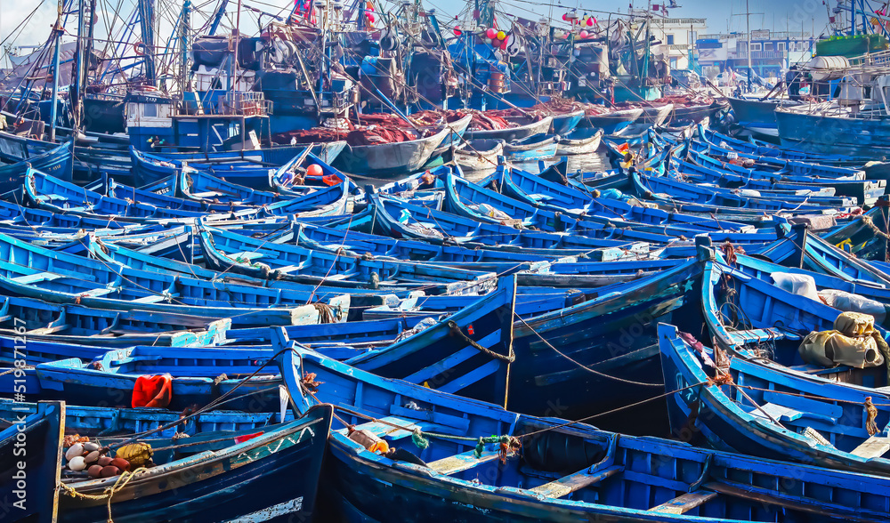 Countless old blue wooden traditional fishing boats crammed together in overcrowded no space full north african harbor  - Essaouira, Morocco