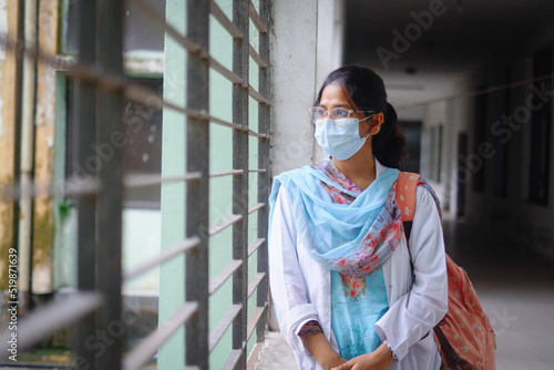 south asian young female doctor in hospital corridor, confident medical student with face mask