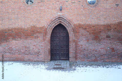 Wooden door in a brick wall, the door is in the Gothic style.