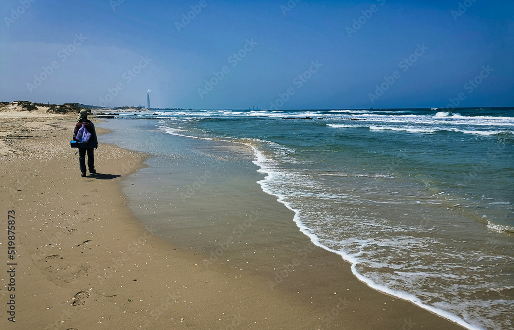 A traveler man walking along a beach, Israel trail A traveler man walking along a beach, Israel trail