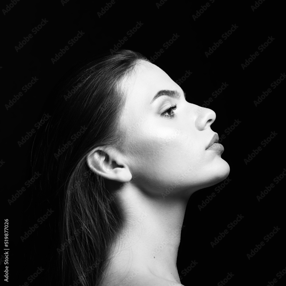 Beauty, make-up and fashion concept. Young and beautiful woman with long  dark hair profile view portrait. Model looking aside the camera in black  studio background. Black and white image Stock Photo