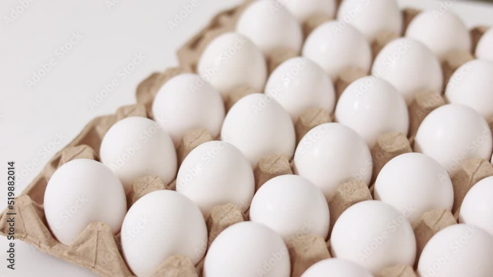 White chicken eggs in a cardboard box. Fresh raw eggs in a paper egg container for store and shop. egg tray with eggs on white table background. Top view. preparation to easter holiday. White chicken eggs in a cardboard box. Fresh raw eggs in a paper egg container for store and shop. egg tray with eggs on white table background. Top view. preparation to easter holiday.