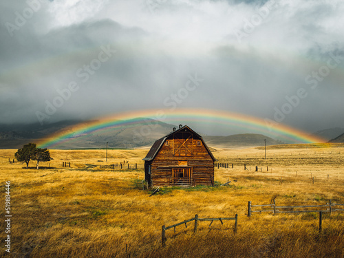 Beautiful barn cabin under a fall rainbow in a golden field photo