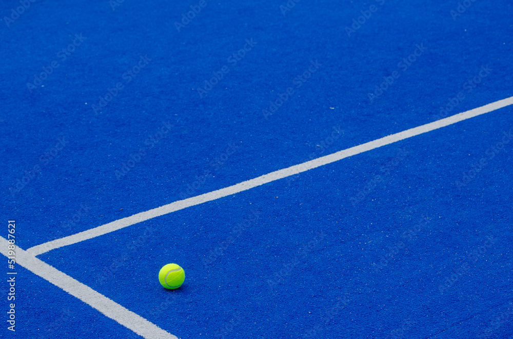 A ball on a blue paddle tennis court, racket sports concept