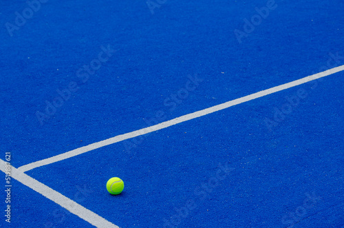 A ball on a blue paddle tennis court, racket sports concept © Vic