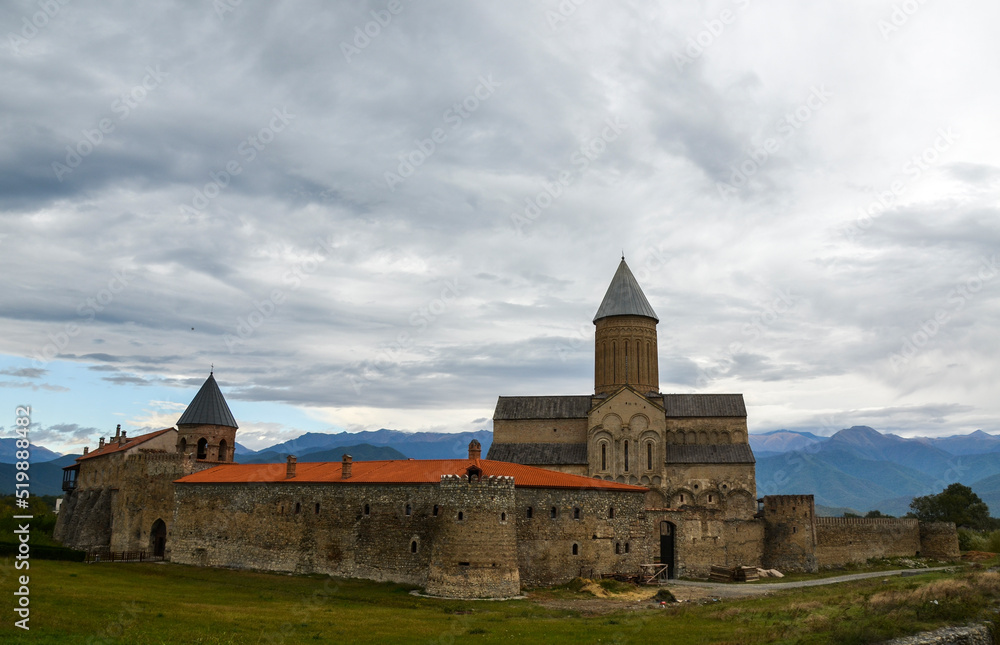 Exterior of Alaverdi Monastery with St. George Cathedral at the foot of the Caucasus Mountains, against cloudy sky. Kakheti region, Georgia