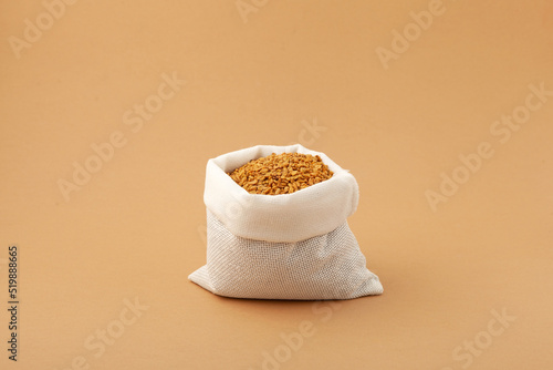 Brown Fenugreek seeds in white pouch. Selective focus, copy space photo