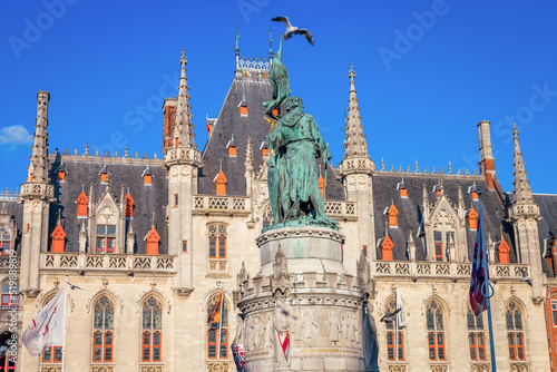 Pigeon flying above Bruges market square, flemish architecture