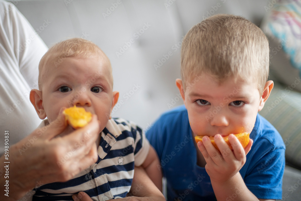 Hermanos comiendo naranja juntos mirando a la cámara Hermanos comiendo naranja juntos mirando a la cámara