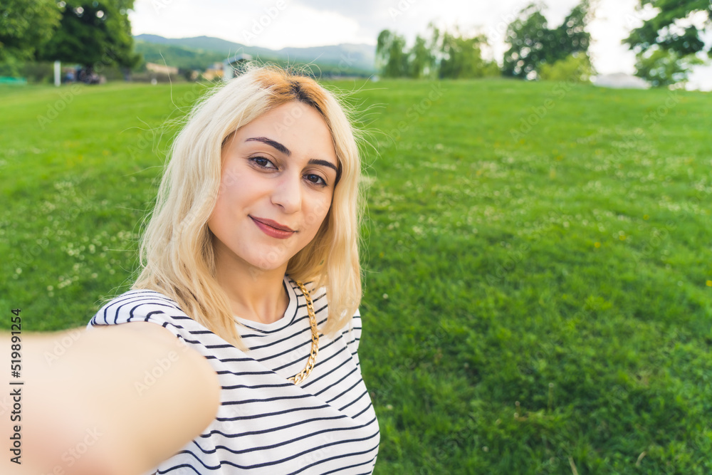blond cheerful girl making a selfie at the park. outdoor medium closeup . High quality photo blond cheerful girl making a selfie at the park. outdoor medium closeup . High quality photo