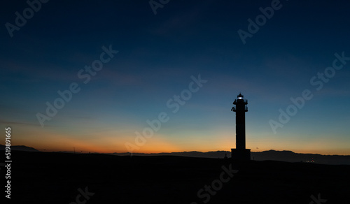 Lighthouse silhouette in Delta de l'ebro Spain during the sunset