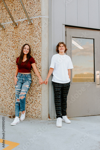 teen boy being silly holding pinkies with girlfriend on garage rooftop photo