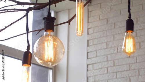 Photos Close up for led light bulbs of different forms hanging on black wires from the ceiling in the room with white brick walls