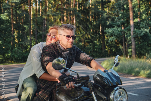 Middle age couple riding a motorcycle, traveling together on a forest road