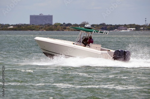 Open sports fishing boat speeding on the Florida `intra-Coastal Waterway off of `Miami Beach