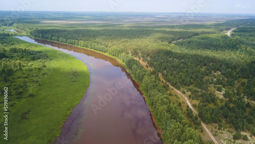 Aerial view of the river and green forest under blue sky in the summer. Clip. Summer landscape with forest, green fields and wide river on a sunny day. © Media Whale Stock