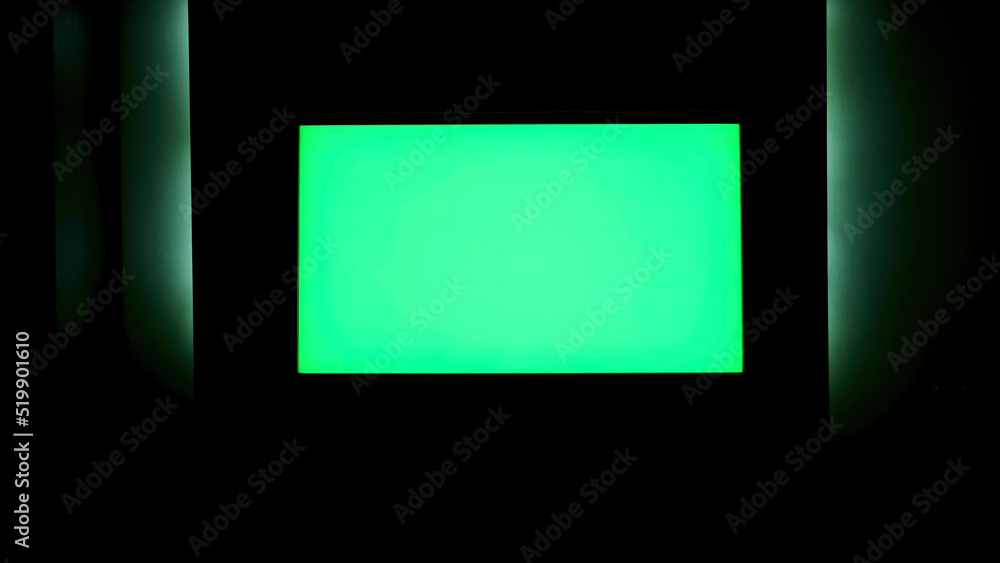 TV with horizontal green screen on a black wall with green illumination ...