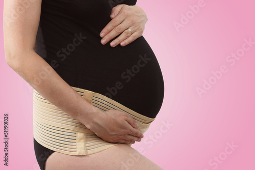 Φωτογραφία Pregnant woman with elastic maternity band on pink background