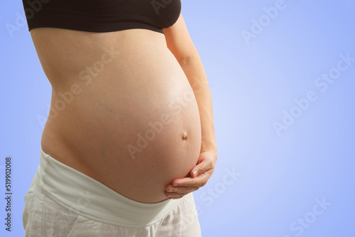Belly of a pregnant woman on the blue background