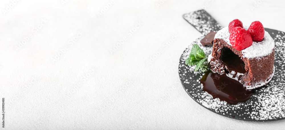 Board with tasty lava cake and raspberry on light background with space for text