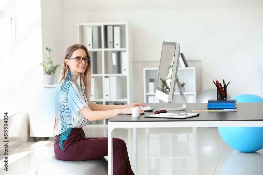 Young businesswoman sitting on fitball while working in office - obrazy, fototapety, plakaty 