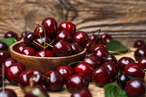 Bowl full of tasty cherries on wooden background, closeup