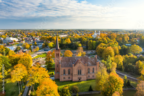 Beautiful aerial view of Evangelical Reformed Church in Birzai surrounded by autumn vegetation on sunny fall day.