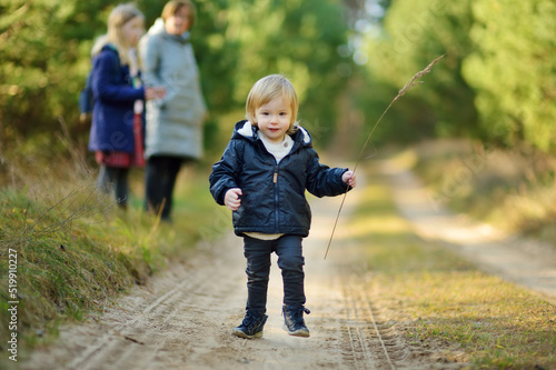Funny toddler boy having fun outdoors on sunny autumn day. Child exploring nature. Autumn activities for small kids.