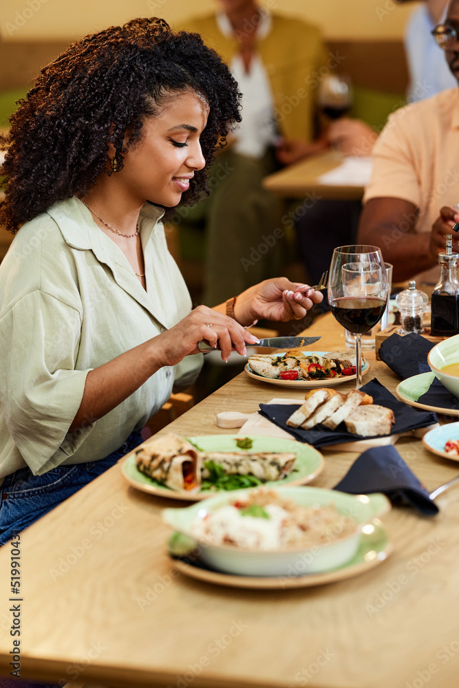 A Hispanic girl sits in the restaurant at the dinner table with her boyfriend and eats dinner. A Hispanic girl sits in the restaurant at the dinner table with her boyfriend and eats dinner.