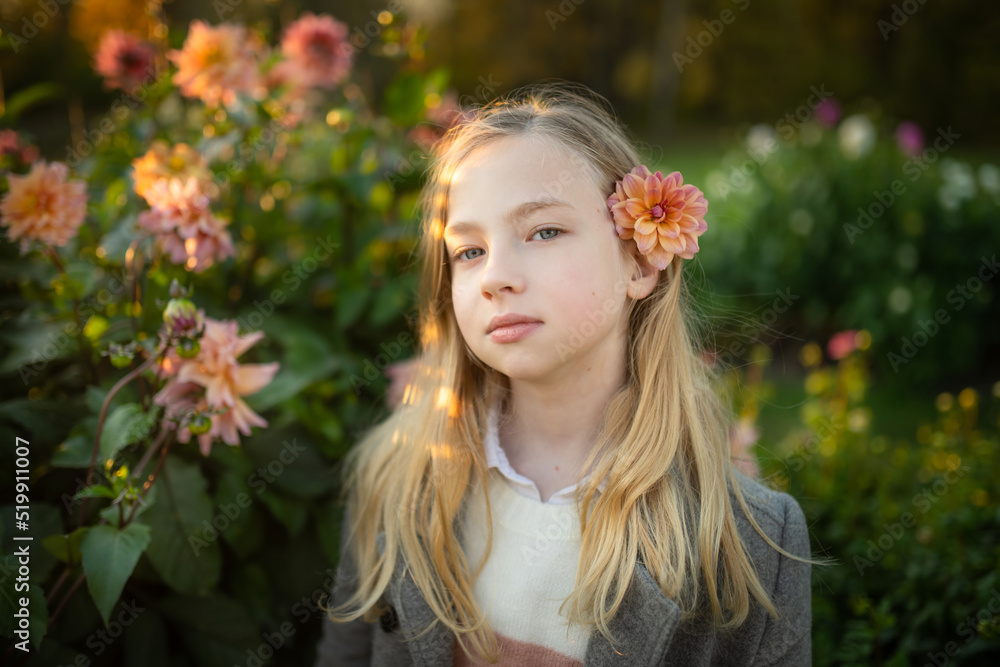 Fototapeta premium Beautiful preteen girl in blossoming dahlia field. Child picking fresh flowers in dahlia meadow on autumn day.