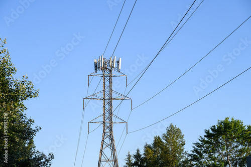 Mobility antennas installed on a power line transmission tower, warm evening light against a blue sky 