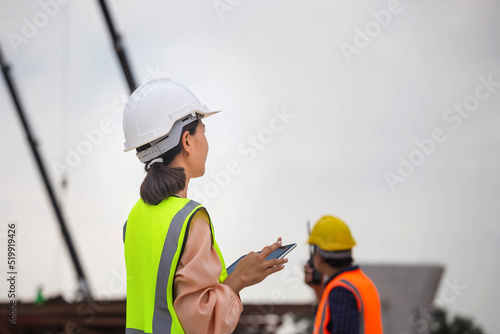 Female engineer and foreman worker checking project at building site, Engineer and builders in hardhats discussing on construction site, Teamwork concepts