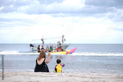 Mother and son waved greetings to father playing boat with friends.