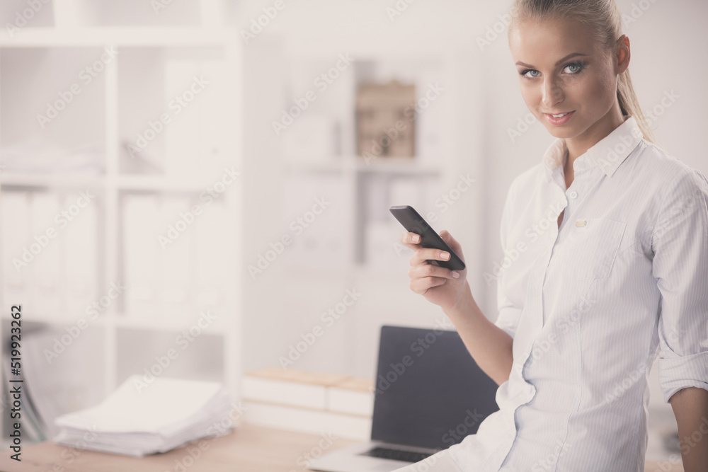 Businesswoman sending message with smartphone in office Businesswoman sending message with smartphone in office
