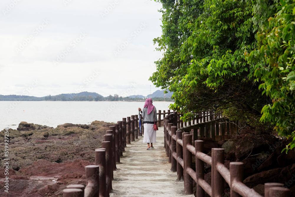 Fototapeta premium Rear view of muslim woman wearing hijab fashion walking on walkway concrete at the island
