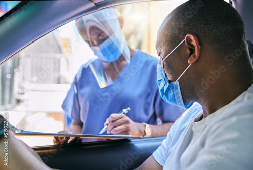 Covid testing centre and drive thru service for patients with coronavirus or getting vaccine. African man in car wearing a protective face mask to avoid contact with medical worker asking questions photo