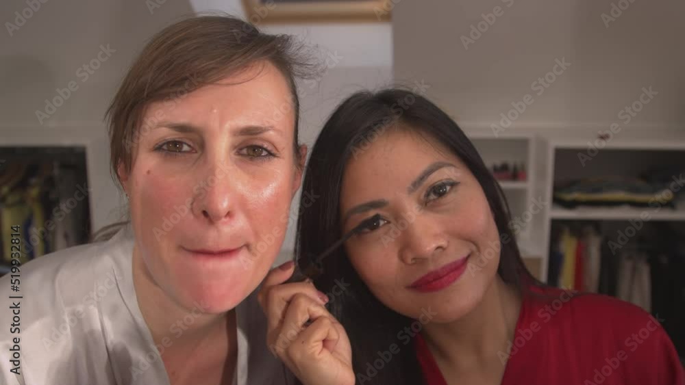 CLOSE UP: Two beautiful women using beauty products for applying face make up. Caucasian and Asian woman getting ready for a girls night out. Attractive ladies having fun while using make up products. CLOSE UP: Two beautiful women using beauty products for applying face make up. Caucasian and Asian woman getting ready for a girls night out. Attractive ladies having fun while using make up products.