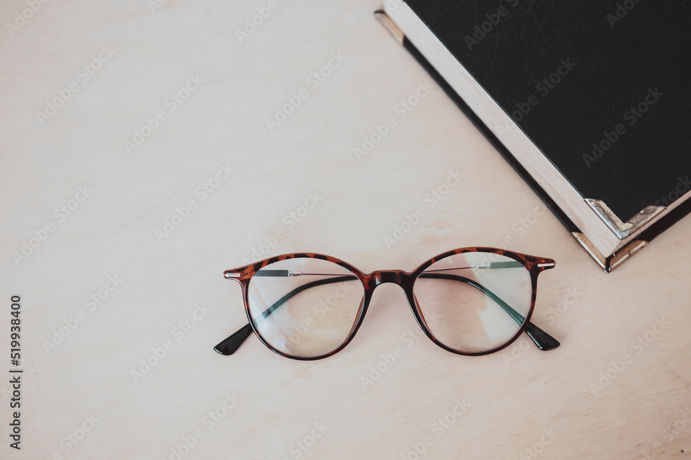 Eye glasses with old book with space on wood background, vintage tone style, business and education concept background Eye glasses with old book with space on wood background, vintage tone style, business and education concept background