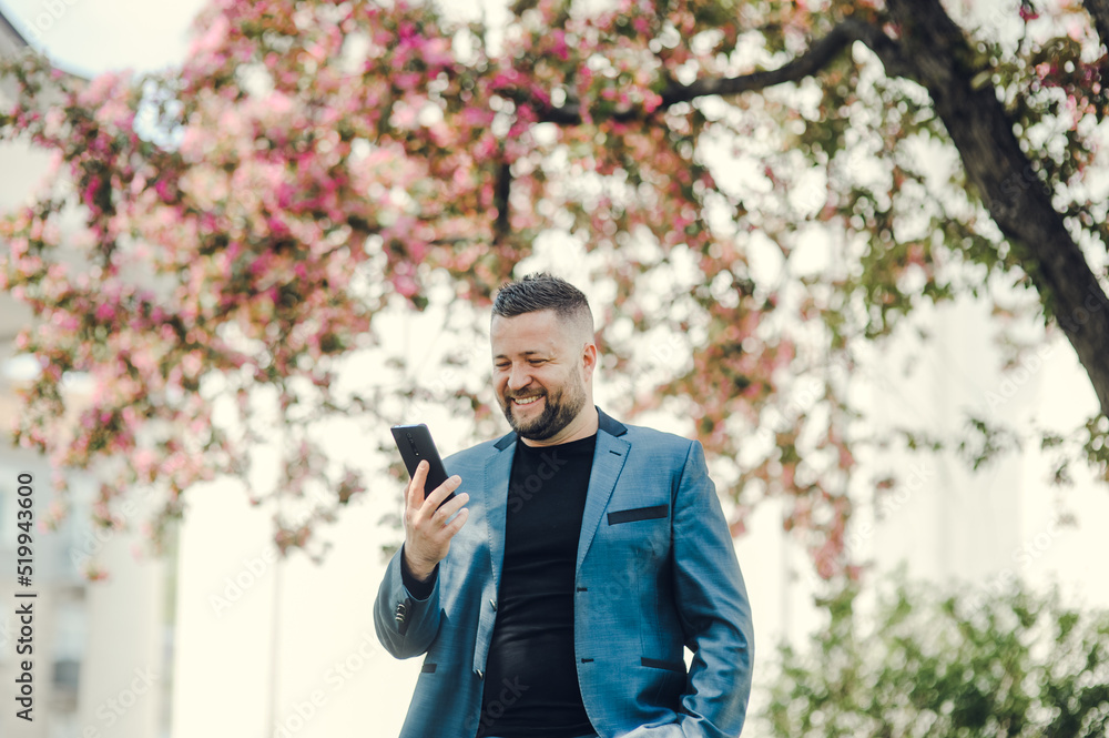 Portrait of handsome successful smiling man near tree in park.Cheerful man with a phone in his hands. Portrait of handsome successful smiling man near tree in park.Cheerful man with a phone in his hands.