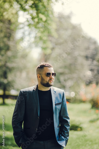 A stylish man in black glasses and a business suit is waiting for a meeting.