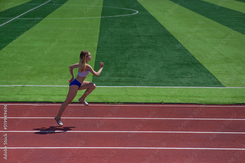 Fototapeta premium Young caucasian woman is engaged in jogging at the stadium outdoors.