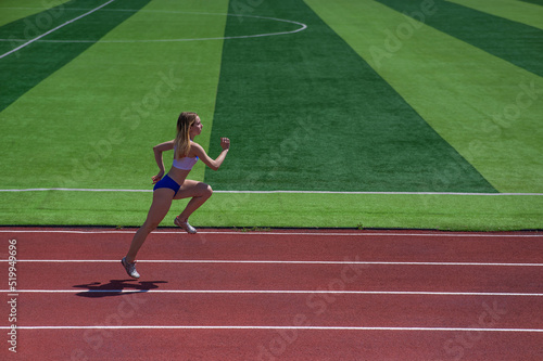 Young caucasian woman is engaged in jogging at the stadium outdoors.