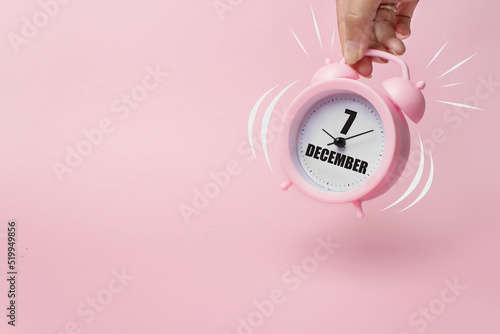 December 7th. Day 7 of month, Calendar date. The morning alarm clock jumping up from the bell with calendar date on a pink background.  Winter month, day of the year concept. photo