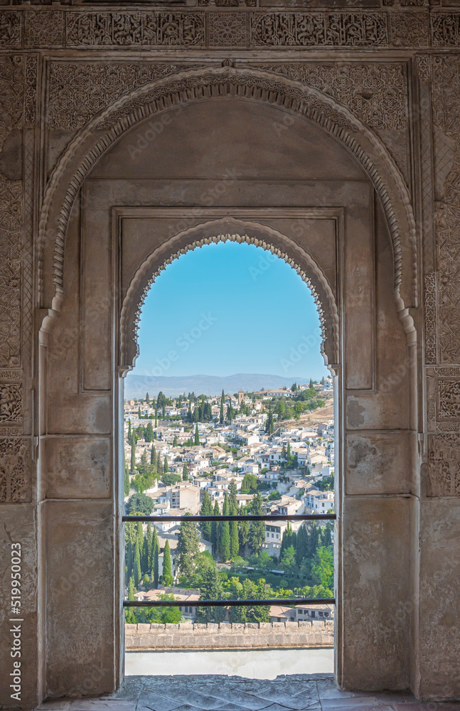 La ciudad de Granada vista a través del marco de una puerta de estilo árabe nazarí en el palacio del Generalife de la Alhambra, España