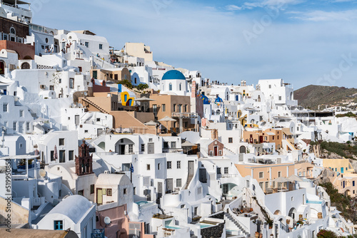 Scenic view of Oia town in Santorini with whitewashed houses and a small church with blue domes, Greece