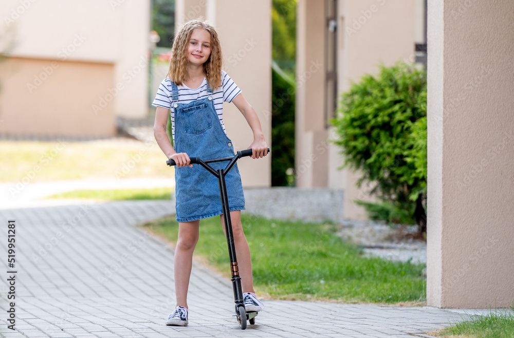 Naklejka premium Little girl rides a kick scooter